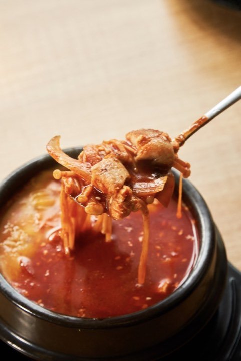 A spoonful lifted from a bowl of sundubu-jjigae