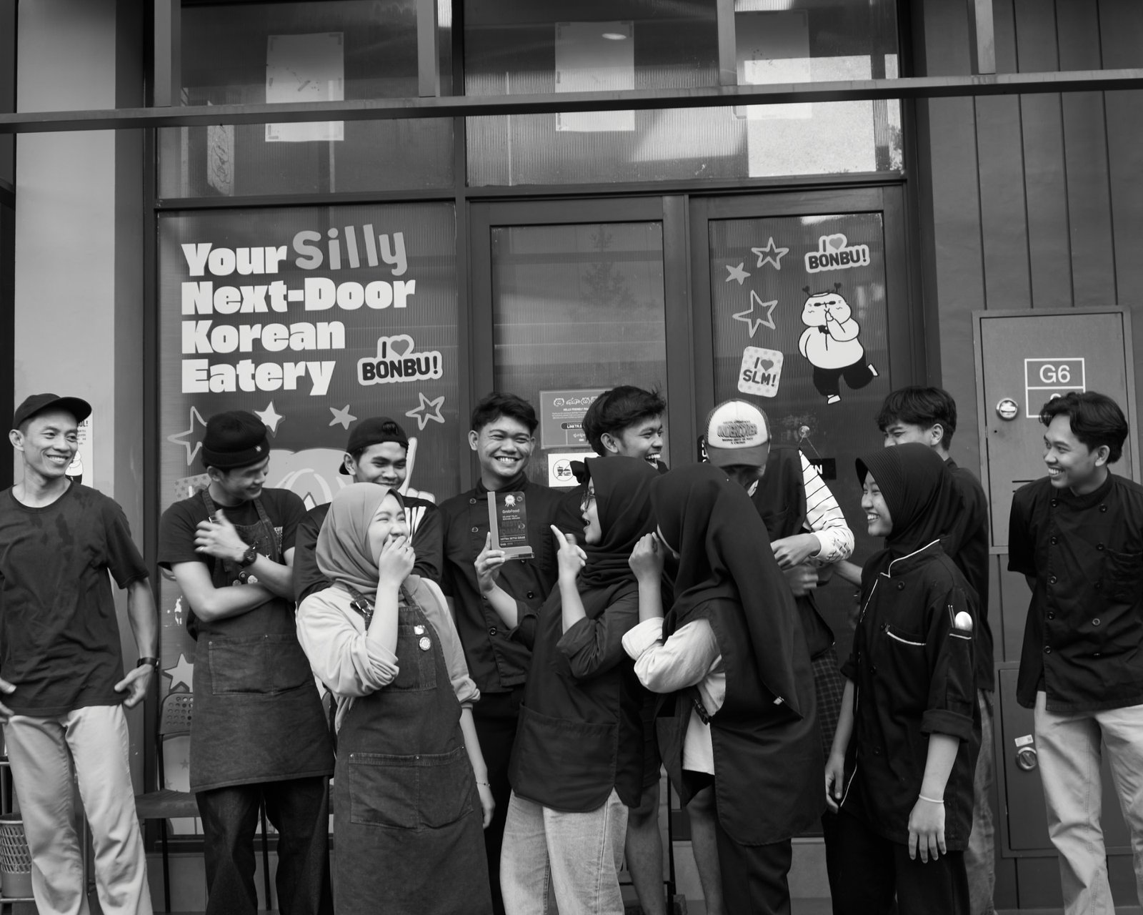 The BONBU team laughing together outside the restaurant, holding a GrabFood award